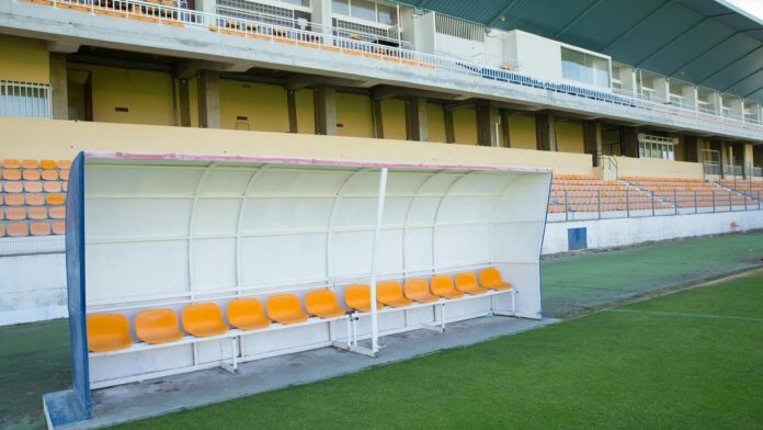 Empty team bench at a football stadium in Portugal, showcasing vibrant seats and lush grass.