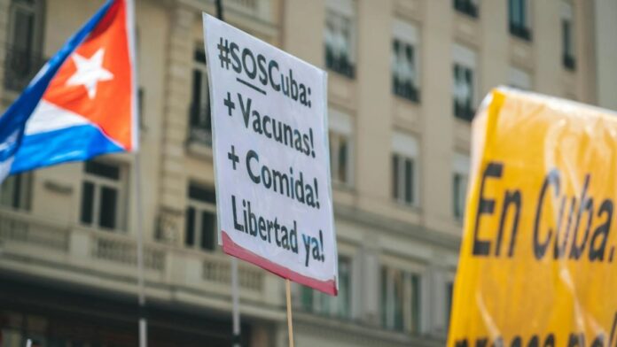 Protest in Cuba showcasing signs demanding more food, vaccines, and freedom.