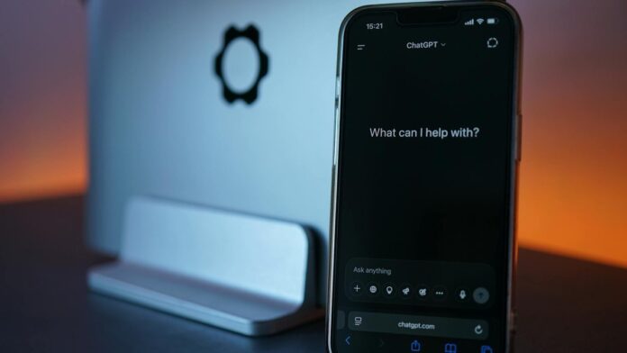 s4-d48935172efd Close-up of a smartphone showing a chat interface with a laptop in the background.