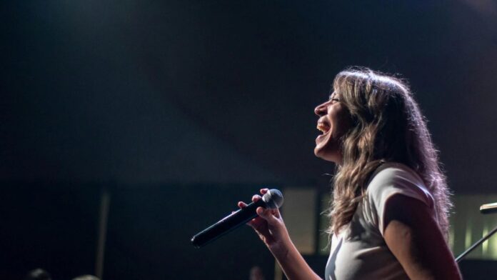 Charismatic female singer performing passionately on stage during a live concert.