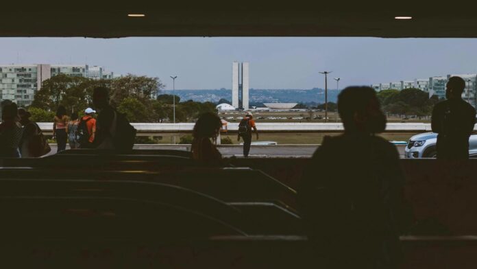 Silhouettes of people in an underpass with Brasília's National Congress in the background.