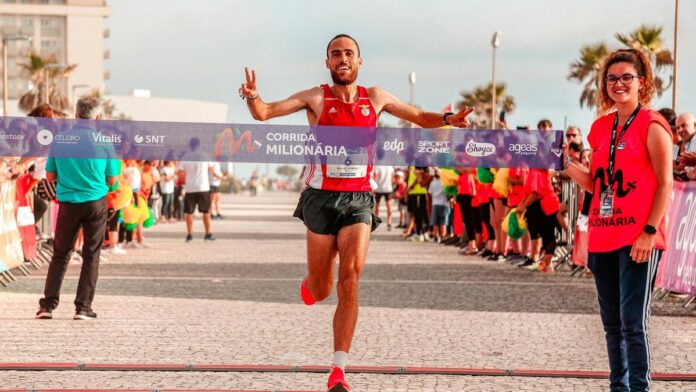 Male runner celebrates crossing the finish line in an outdoor marathon race.