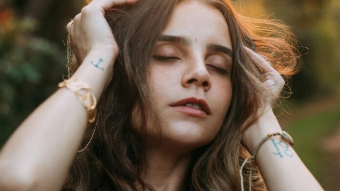 s4-eae0404bcc25 Close-up portrait of a serene woman outdoors, eyes closed, at sunset in Dourados, Brazil.