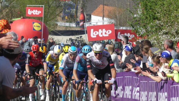 Cyclists race past cheering spectators at a competition.