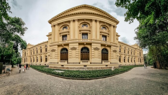 Panoramic view of historic architectural structure in São Paulo, surrounded by trees and visitors.