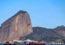 Estreito de Ormuz: tráfego de navios segue paralisado após cessar-fogo Container ship passing by Sugarloaf Mountain in Rio de Janeiro on a clear day, showcasing global trade.