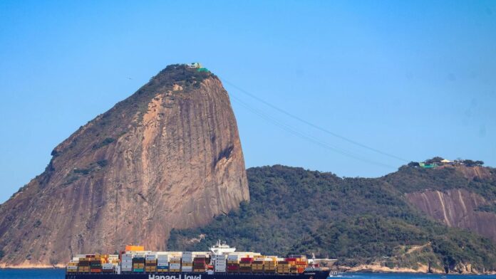Container ship passing by Sugarloaf Mountain in Rio de Janeiro on a clear day, showcasing global trade.