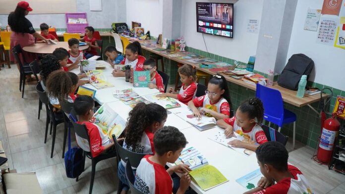 s4-f192ef52c543-3 Children engaged in reading at a community library in Glória do Goitá, Brazil.