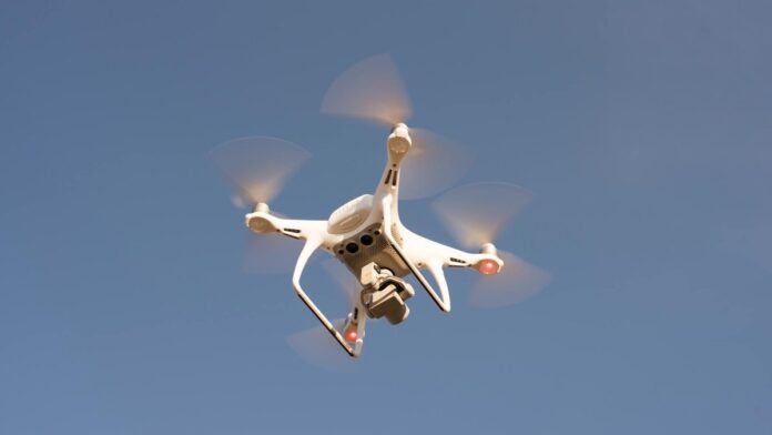 A white drone in flight against a clear blue sky, capturing aerial footage with precision.