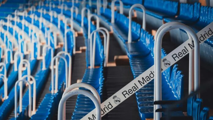 Rows of blue stadium seats in Madrid's iconic Bernabéu Stadium, featuring Real Madrid branding.