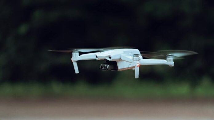 A close-up shot of a white drone flying outdoors in a natural setting.