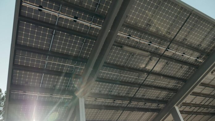 Close-up of solar panels on metal structure with sunlight filtering through, emphasizing sustainable energy.