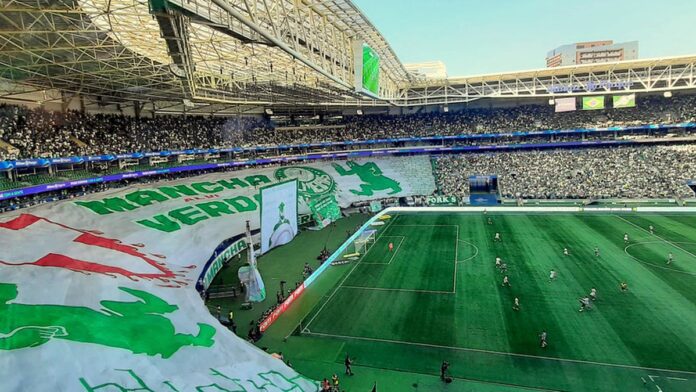 Atacante Rony, com uniforme do Palmeiras, em campo durante partida de futebol, olhando para a frente com foco.