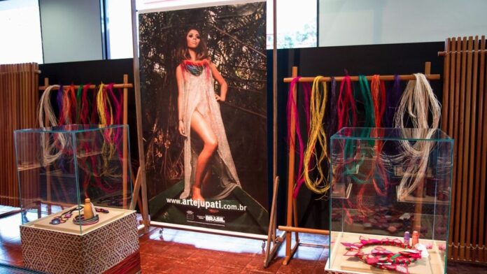 Fachada de prédio público com bandeiras do Brasil e do Pará hasteadas sob céu azul ensolarado.