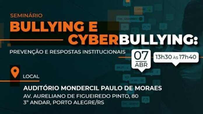 Auditório com participantes sentados diante de telão exibindo palestra sobre combate ao bullying e cyberbullying.
