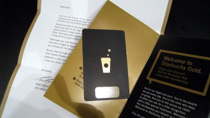 Executivos apertam as mãos em frente a um logotipo da Starbucks, celebrando parceria estratégica em escritório na China.