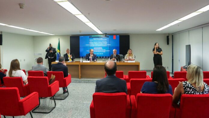 Fachada do prédio do Tribunal do Júri, com colunas de concreto e bandeiras do Brasil ao lado da entrada principal.
