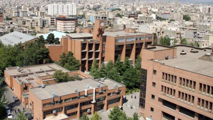 universidade-de-tecnologia-no-ir-bombardeada-por-f Prédio universitário com fachada destruída por explosões, fumaça escura e escombros espalhados no local.