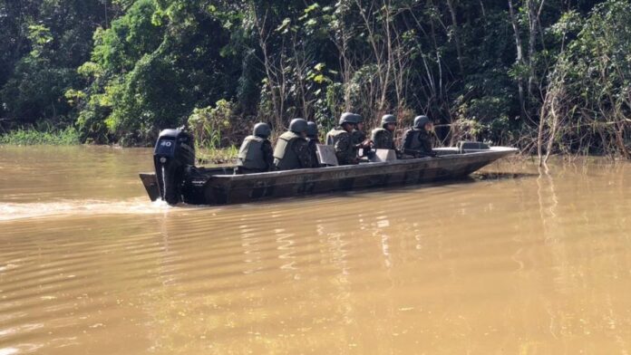 Agentes do Ibama em barco na Amazônia, exibindo apreensões de armas e pescado sobre uma lona em operação de fiscalização.
