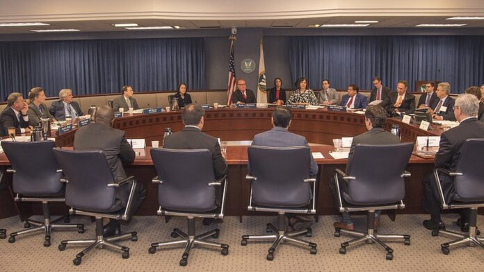 venda-de-usina-pode-ser-barrada-na-ferc-por-omiss- Fachada de um edifício governamental com logotipos de agências reguladoras e símbolos de energia e tecnologia.